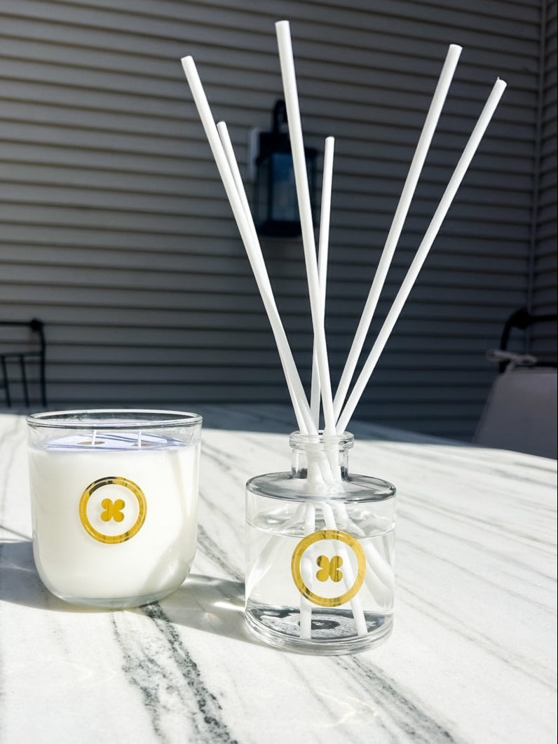 Candle in the sun in glass vessel with shiny gold branding