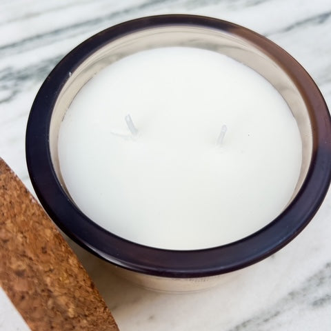White candle in a brown container on a marble surface