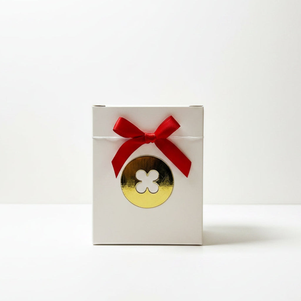 White box with a gold button and red bow on a marble surface