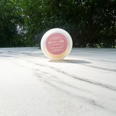 Solid lotion bar on a marble surface with greenery in the background
