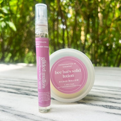 Bee bars solid lotion and container on a marble surface with a greenery background
