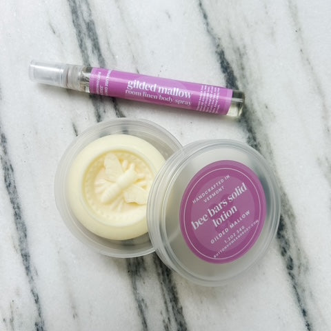 Solid lotion bar and container with  on a marble surface