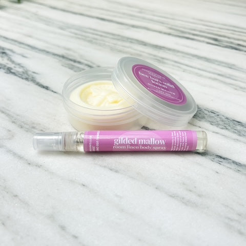 solid lotion bar with spray bottle on a marble surface with greenery in the background