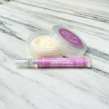 solid lotion bar with spray bottle on a marble surface with greenery in the background