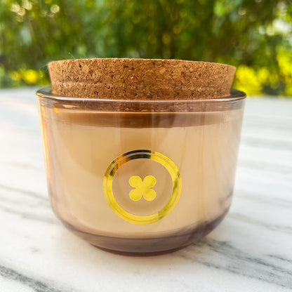 Glass container with cork lid on a marble surface with greenery in the background