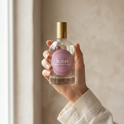 Icon room and linen spray held upright in a hand beside a sunlit window.