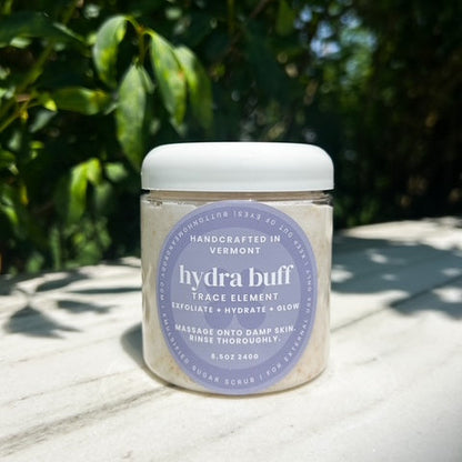 Jar of 'hydra buff' on a marble surface with greenery in the background