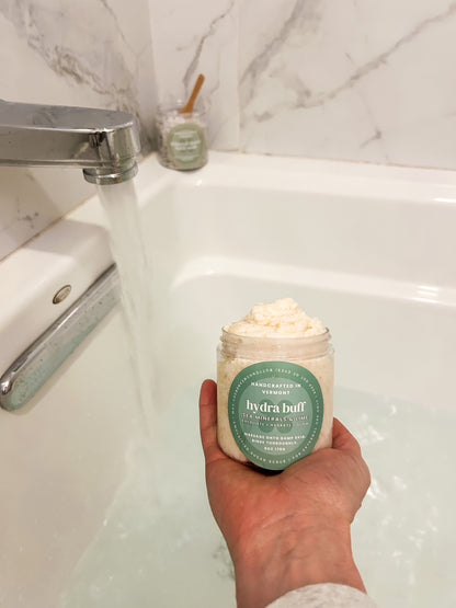 hand holding jar of sugar scrub with water running in a bath tub l